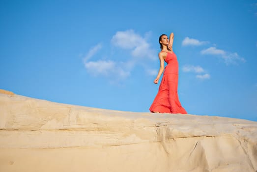 Portrait of a beauty woman in red dress on the desert