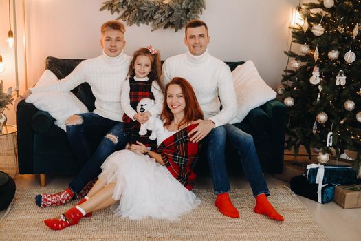 Close-up portrait of a happy family sitting on a sofa near a Christmas tree celebrating a holiday.