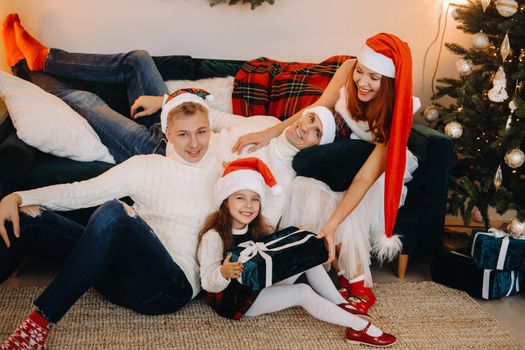 Close-up portrait of a happy family sitting on a sofa near a Christmas tree celebrating a holiday.