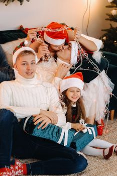 Close-up portrait of a happy family sitting on a sofa near a Christmas tree celebrating a holiday.