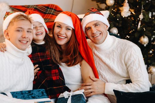 Close-up portrait of a happy family sitting on a sofa near a Christmas tree celebrating a holiday.