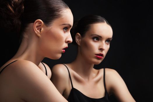 Beautiful sexy young woman near a mirror over black background