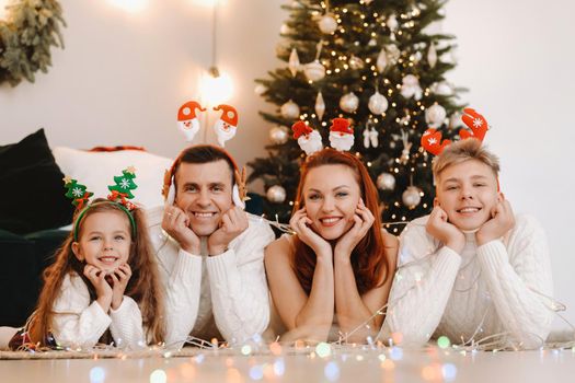 Close-up portrait of a happy family lying near a Christmas tree celebrating a holiday.