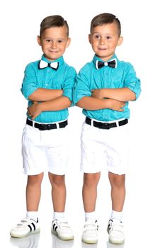 Two cute little boys stand in front of the camera in full growth. The concept of a happy childhood, the development of a child in the family. Isolated on white background.