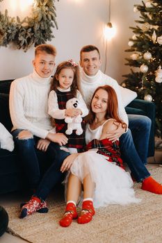 Close-up portrait of a happy family sitting on a sofa near a Christmas tree celebrating a holiday.