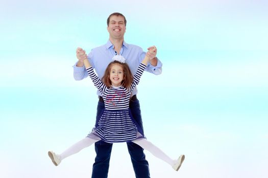 Happy young dad raise his beloved daughter's hands.On the background of summer blue sky and fluffy clouds.