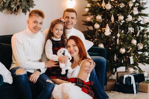 Close-up portrait of a happy family sitting on a sofa near a Christmas tree celebrating a holiday.