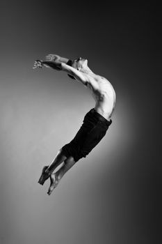 Caucasian man gymnastic leap posture on grey background