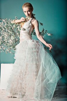 Portrait of a woman in wedding dress behind the branches with flowers