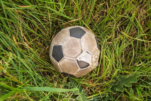 Old Soccer ball on the green grass, top view.