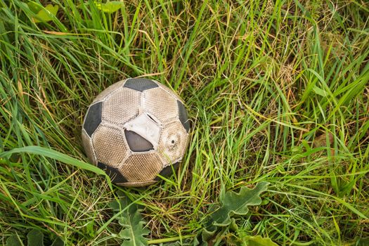 Old Soccer ball on the green grass, top view.