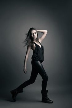 Fashion model wearing leather pants posing on grey background