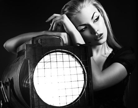 Sexy young woman with old floodlight over dark background