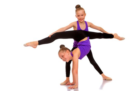 Lovely little girls gymnasts warm up before the competition. The concept of a happy childhood, sports and fitness. Isolated on white background.