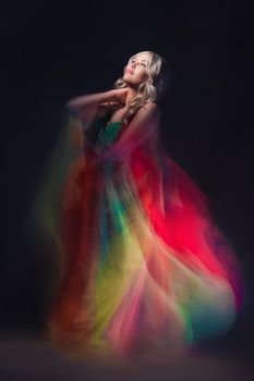 Young beautiful female model in colorful dress on black background