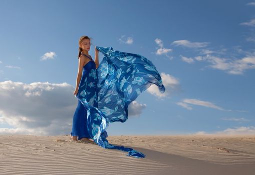 Portrait of a beauty woman in blue dress on the desert