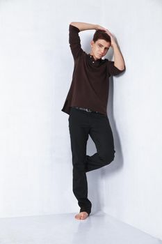 Young male fashion model posing in a casual outfit on grey background