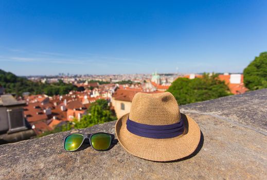 Tourism, travel, holidays and summer concept - Hat and sunglass against an old city background