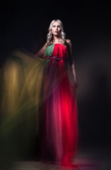 Young beautiful female model in colorful dress on black background