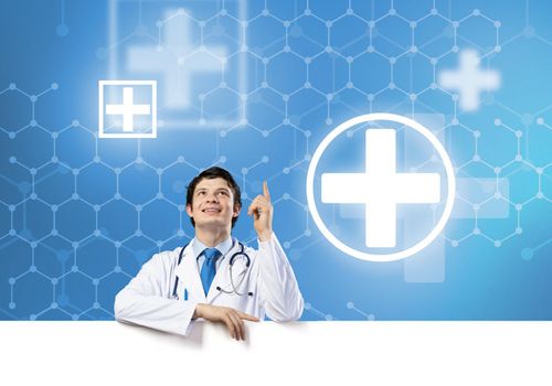 Young handsome doctor holding white blank banner. Place your text