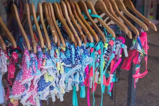 Choice of fashion clothes of different colors on wooden hangers.