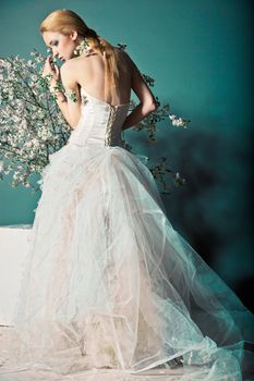 Portrait of a woman in wedding dress behind the branches with flowers