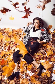 Young brunette woman portrait in lying autumn leaves