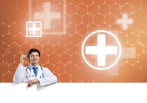 Young handsome doctor holding white blank banner. Place your text