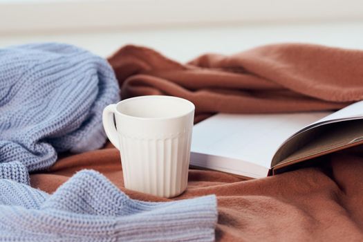 a blanket near the window a cup of coffee book Comfort rest. High quality photo