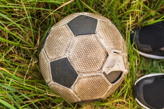 Old Soccer ball on the green grass, top view.