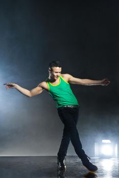 Modern style dancer posing on dark background with flashes and smoke