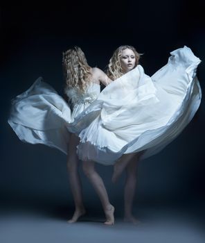 Fine art photo of a dancing beautiful young girl in white wedding dress with multiexposition