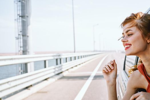 cheerful woman peeking out of the car window trip road travel. High quality photo