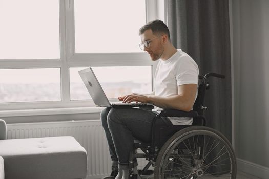 Disabled man using laptop. Cheerful handsome man stay at home and work remotely.