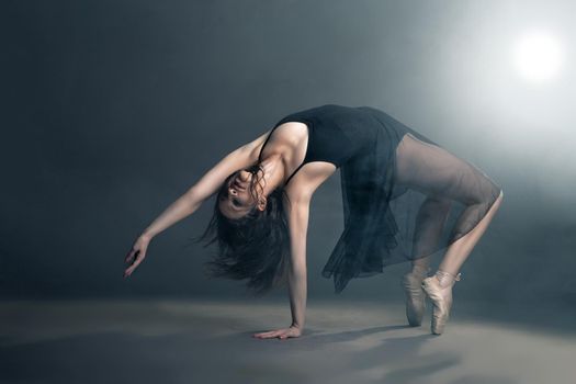 Modern style dancer posing on a studio grey background in fog