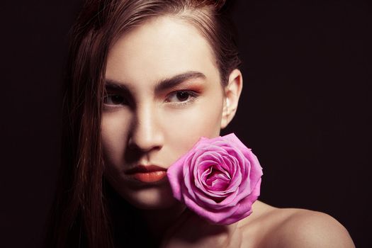 close-up portrait of beautiful brunette woman with pink rose