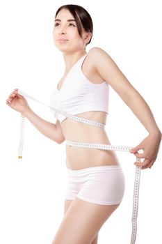 slimming woman measuring her thigh with measuring tape over white background