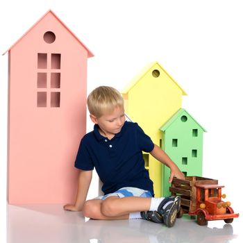 Cute little boy is playing with a toy wooden car on a white background in the studio. The concept of a happy childhood, learning and education in the family. Isolated.