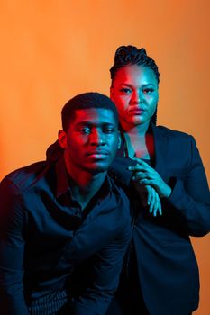 Dark neon portrait of young african american man and woman. Red and blue