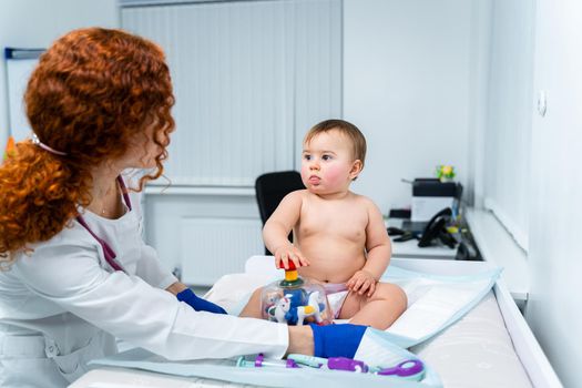 Pediatrician providing healthcare for her baby patient in the office of a specialized clinic for children. Neonatologist. Medical appointment little child one year old in the clinic. Health care of infant, children, kid.