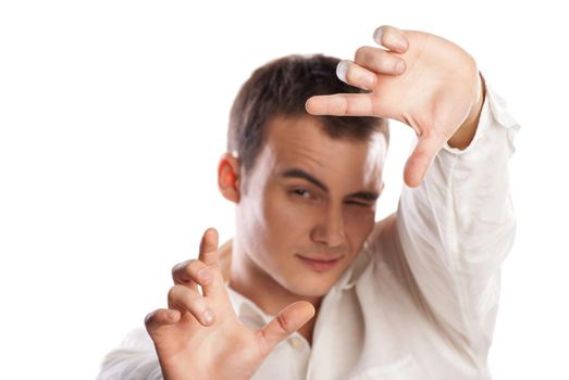 Portrait of smiling young man making frame with finger against white background