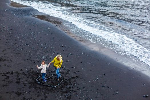 Family holiday on Tenerife, Spain, Europe. Mother and daughter outdoors on ocean. Portrait travel tourists - mom with child. Positive human emotions, active lifestyles. Happy young family on sea beach