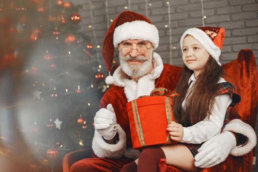 Christmas, child and gifts. Santa Claus brought gifts to kid. Joyful little girl hugging Santa.