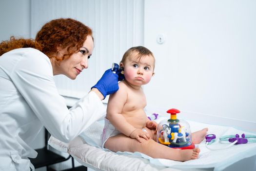 Pediatrician providing healthcare for her baby patient in the office of a specialized clinic for children. Neonatologist. Medical appointment little child one year old in the clinic. Health care of infant, children, kid.