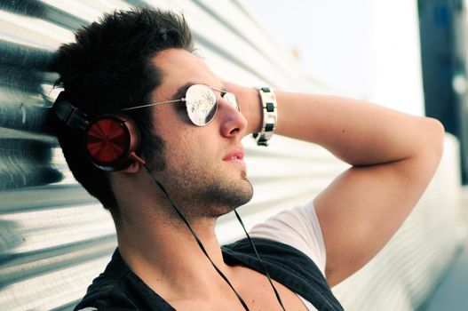 Portrait of handsome man in urban background listening to the music with headphones
