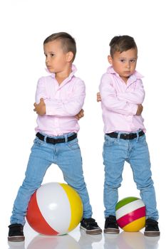 Two cute little boys stand in front of the camera in full growth. The concept of a happy childhood, the development of a child in the family. Isolated on white background.