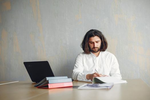 Handsome man in a white shirt. Businessman working at the office. Guy with a laptop.