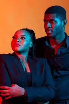 Dark neon portrait of young african american man and woman. Red and blue