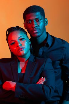 Portrait of young african american couple in love posing at studio dressed in classic clothes. Neon light