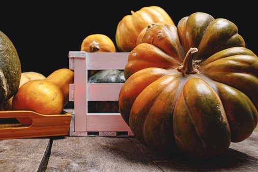 Pile of pumpkins in wooden box on old wooden board